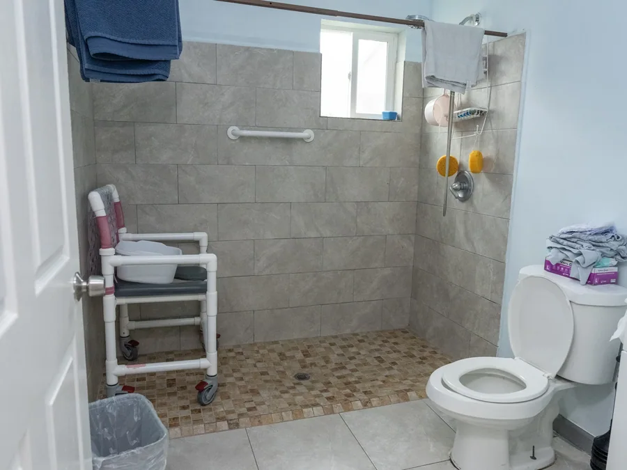 Wheelchair-accessible bathroom with roll-in shower, grab bars, and safety equipment.
