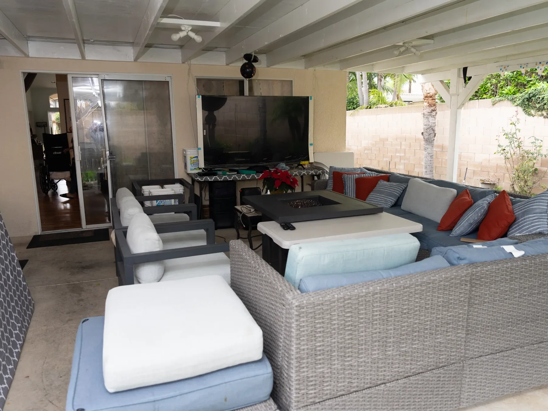 Covered patio with comfortable seating, entertainment area, and fire pit.